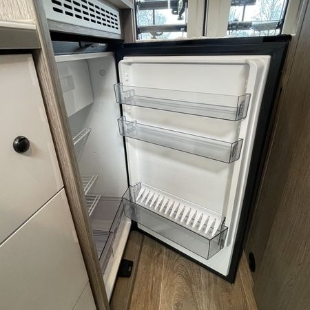 Innenansicht eines offenen Kühlschranks mit leeren Regalen und Schubladen in einer modernen Küche