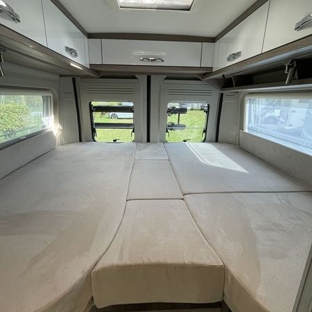 Indretning af en autocamper med en hyggelig seng med blødt sengetøj og opbevaringsrum