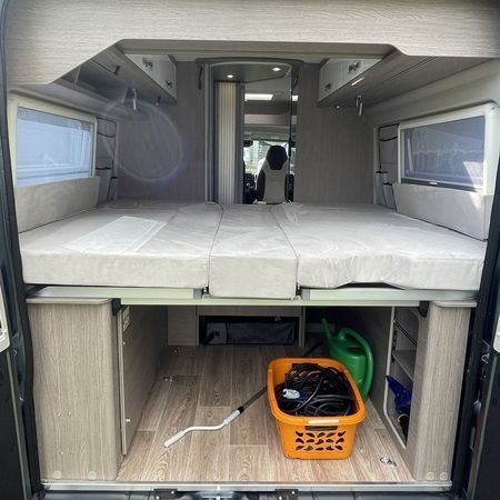 Et hyggeligt autocamperinteriør med en pænt redt seng