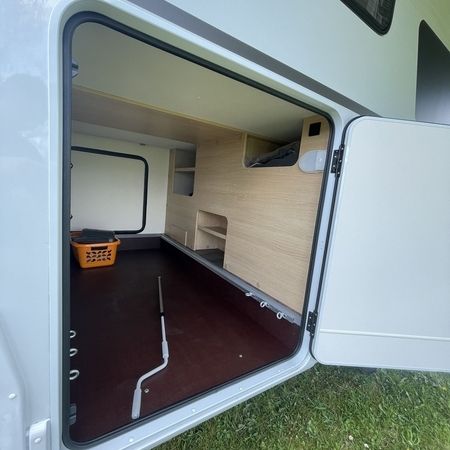 Indvendigt billede af en autocamper med åben dør, der viser opbevaringsplads