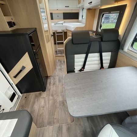 Indvendigt i en autocamper med kompakt køkken og hyggelig spiseplads med siddepladser