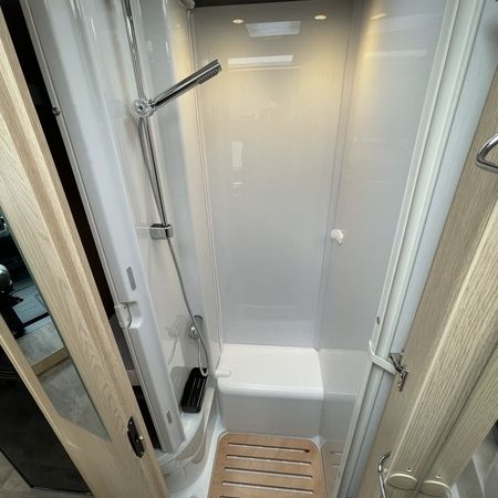 Et brusebad med trægulv og moderne brusehoved