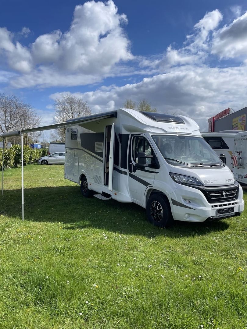 Autocamper parkeret på en græsplæne med udfoldet markise